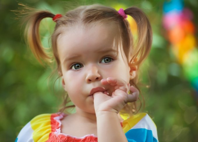 Toddler girl with pigtails sucking her thumb