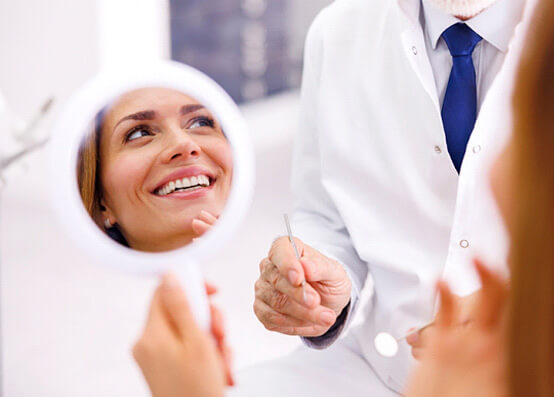 patient smmiling while holding handheld mirror