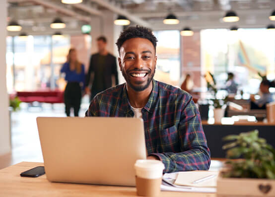 man smiling while working on laptop in office