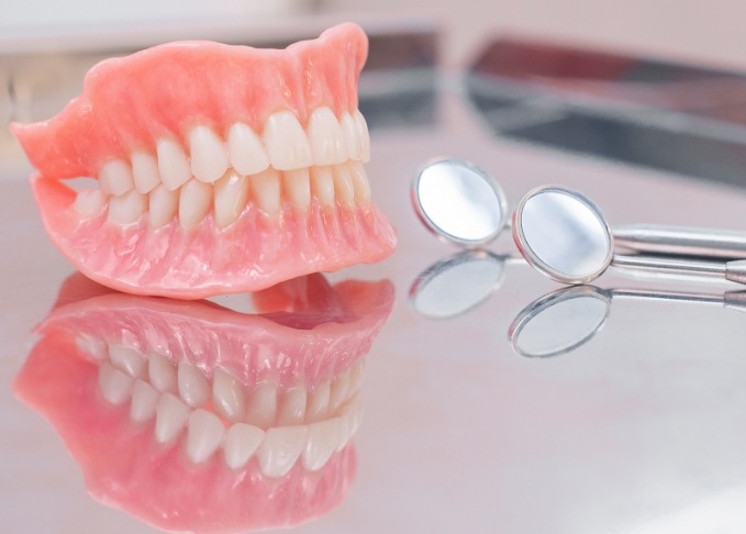 Dentures in Bedford on table next to two dental mirrors