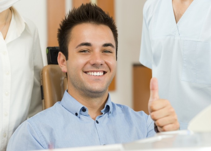 man in dental chair smiling and giving thumbs up