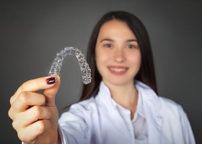 Young woman holding an Invisalign aligner